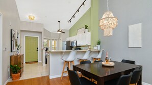 A modern kitchen with white cabinets, a dining area with a dark wooden table and black chairs, a green door, and a ceiling fan. - 5*Star Coral Falls, 2BR Condo, Naples FL USA, 15min drive to many beaches, shops (Naples)