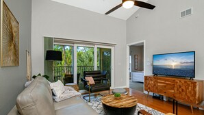 A modern living room with a leather sofa, a coffee table, a TV on a wooden cabinet, and a balcony with a view of greenery. - 5*Star Coral Falls, 2BR Condo, Naples FL USA, 15min drive to many beaches, shops (Naples)