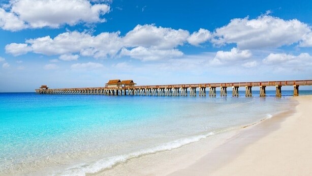 A beach with a wooden pier extending into the ocean, featuring overwater bungalows. - 5*Star Coral Falls, 2BR Condo, Naples FL USA, 15min drive to many beaches, shops (Naples)
