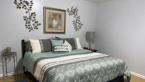A bedroom with a bed, bedside table, lamp, and a wall-mounted picture. - Cozy Apartment (sleeps 6) (Kodak)