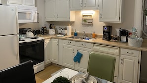 A compact kitchen with white cabinets, a microwave, a stove, and a coffee maker. - Cozy Apartment (sleeps 6) (Kodak)