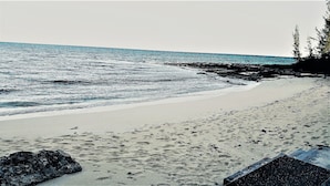 En strand med en stenig kustlinje och fri utsikt över havet.
