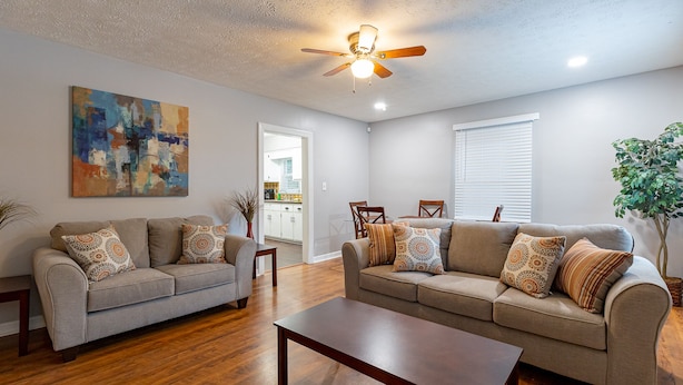 A living room with two sofas, a coffee table, and a ceiling fan.