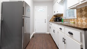 A kitchen with white cabinets, a stainless steel refrigerator, and a tiled backsplash.