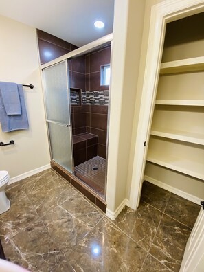 Une salle de bain avec une douche à parois de verre, des toilettes et un sol en marbre.