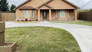 A two-story house with a front porch, a driveway, and a well-maintained lawn.