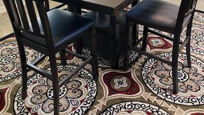 A dining table set with blue dishes and white vases, surrounded by dark wooden chairs on a patterned rug.