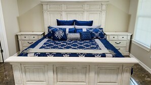 A bedroom with a large bed, white headboard, and marble flooring.