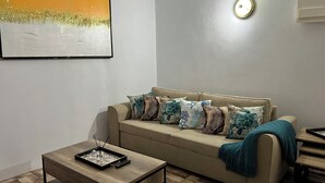 Ein Wohnzimmer mit einem beigen Sofa, einem Couchtisch und einem Gemälde an der Wand.