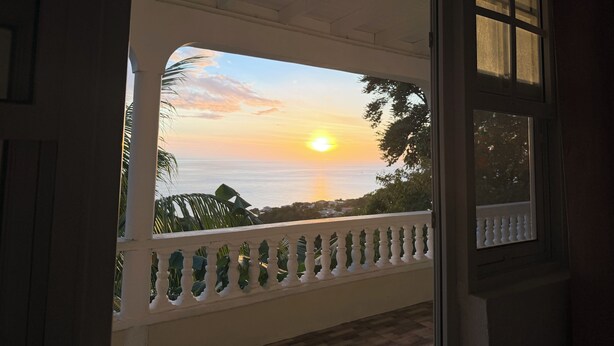 Ein Balkon mit Blick auf den Sonnenuntergang über dem Meer.