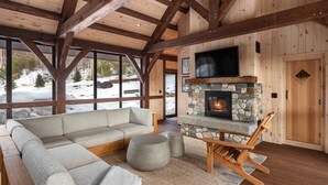A cozy living room with a stone fireplace, a large sectional sofa, and a wooden bench.