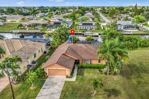 Stroll through a serene residential neighborhood with a beautifully manicured lawn and lush greenery surrounding a charming home.