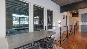 A modern kitchen with a wooden table and chairs, a staircase, and a view of the outdoors.