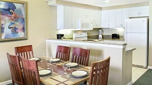 Comedor con una mesa de madera dispuesta para cuatro personas, rodeada de sillas de madera con cojines azules.
