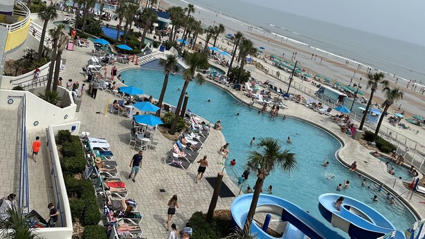 Un resort con piscina, playa y palmeras.