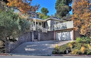 A two-story house with a covered porch, a garage, and a stone wall. - Beautiful large entire house with remodelled backyard (Sherman Oaks)