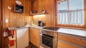 A wooden cabin interior with a kitchen featuring a stove, oven, and sink.