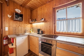 A wooden cabin interior with a kitchen featuring a stove, oven, and sink.
