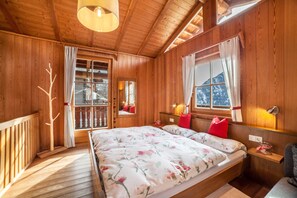 A wooden cabin bedroom with a bed, a nightstand, a window, and a mirror.