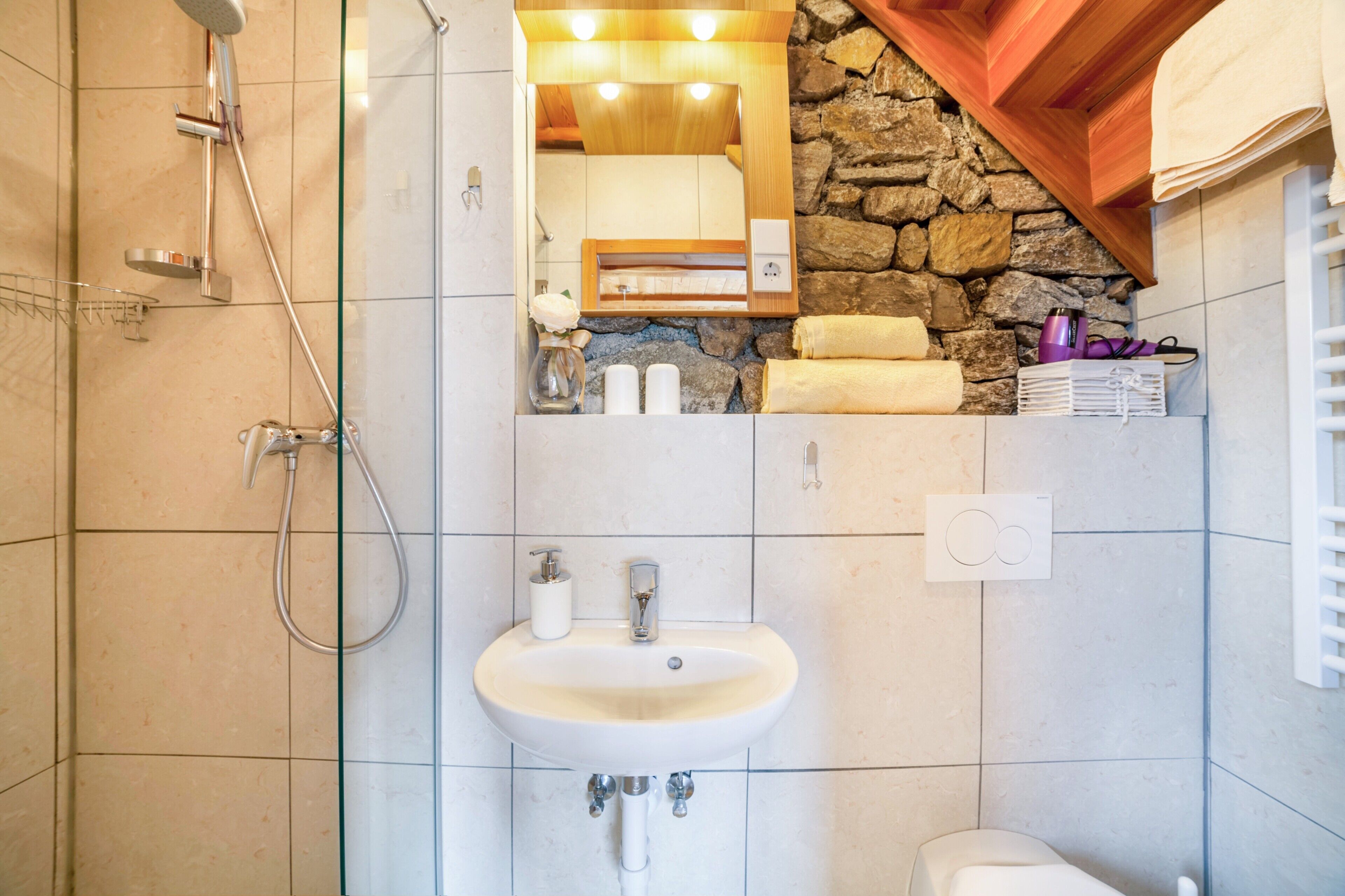 Ein Badezimmer mit Dusche, Waschbecken, Spiegel und Handtuchhalter.