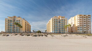 A beachfront hotel with multiple floors, balconies, and palm trees. - Beachfront Penthouse with Wi-fi & Pool (San Javier, Murcia)
