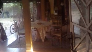 A room with a table and chairs, a bicycle outside, and a window with a view.