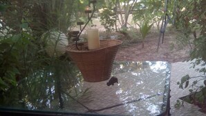 A glass table with a wicker basket containing a candle and a small figurine.