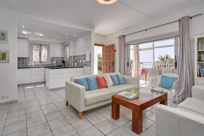 A modern kitchen with white cabinets and a dining area with a white sofa and a wooden table. - Villa "Casa Bonita" with Stunning Views & Heated Pool (Salobreña)