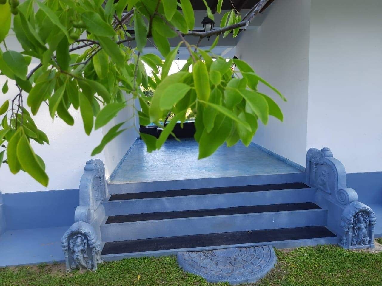 A set of stone steps leading to a building entrance, flanked by decorative stonework.