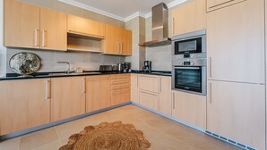 A modern kitchen with wooden cabinets, a Bosch oven, and a coffee maker. - Apartment 'Beachfront Atlantic View A09' with Sea View and Wi-Fi (Óbidos)