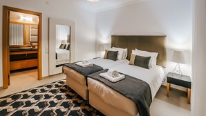 A hotel room with a bed, bedside tables, a mirror, a wardrobe, and a patterned rug. - Apartment 'Beachfront Atlantic View A09' with Sea View and Wi-Fi (Óbidos)
