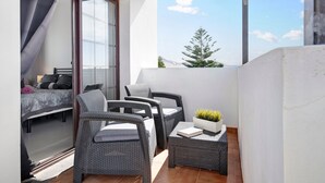 A balcony with wicker furniture, a bed, and a potted plant. - 'Casa Hibiscus' with Private Pool, Jacuzzi, Terrace & Garden (Playa Blanca)