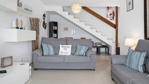 A living room with a grey sofa, a staircase, and a bookshelf. - 'Casa Hibiscus' with Private Pool, Jacuzzi, Terrace & Garden (Playa Blanca)