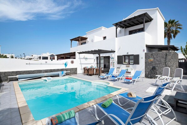 Un hôtel moderne doté d’une piscine, de chaises longues et d’un mur en pierre.