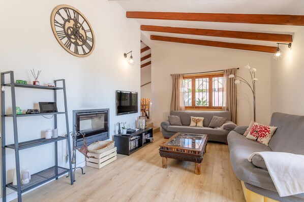 Ein Wohnzimmer mit einer Couch, einem Couchtisch, einem Fernseher, Regalen und einer großen Uhr.