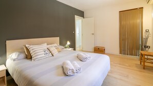 Une chambre à coucher comprenant un lit, une table de chevet, une lampe, un plancher en bois et une porte coulissante.
