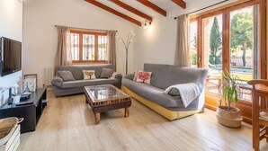 Un salon avec un canapé, une table basse, un téléviseur et une fenêtre avec des rideaux.