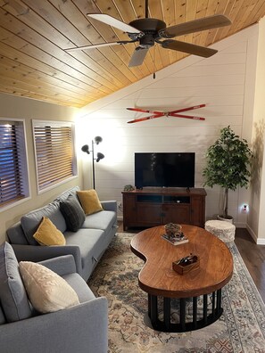 A modern living room with a grey sofa, wooden coffee table, ceiling fan, and a flat-screen TV. - 200,000 acre Los Padres National Forest as a back yard  (Frazier Park)