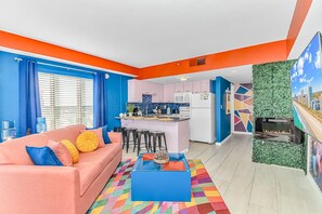 A modern apartment with a kitchen, living room, and a colorful rug.
