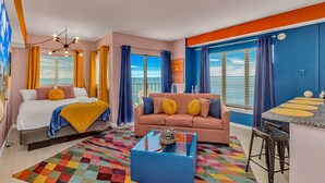 Ein modernes Hotelzimmer mit Bett, Sofa und einer kleinen Küchenzeile.