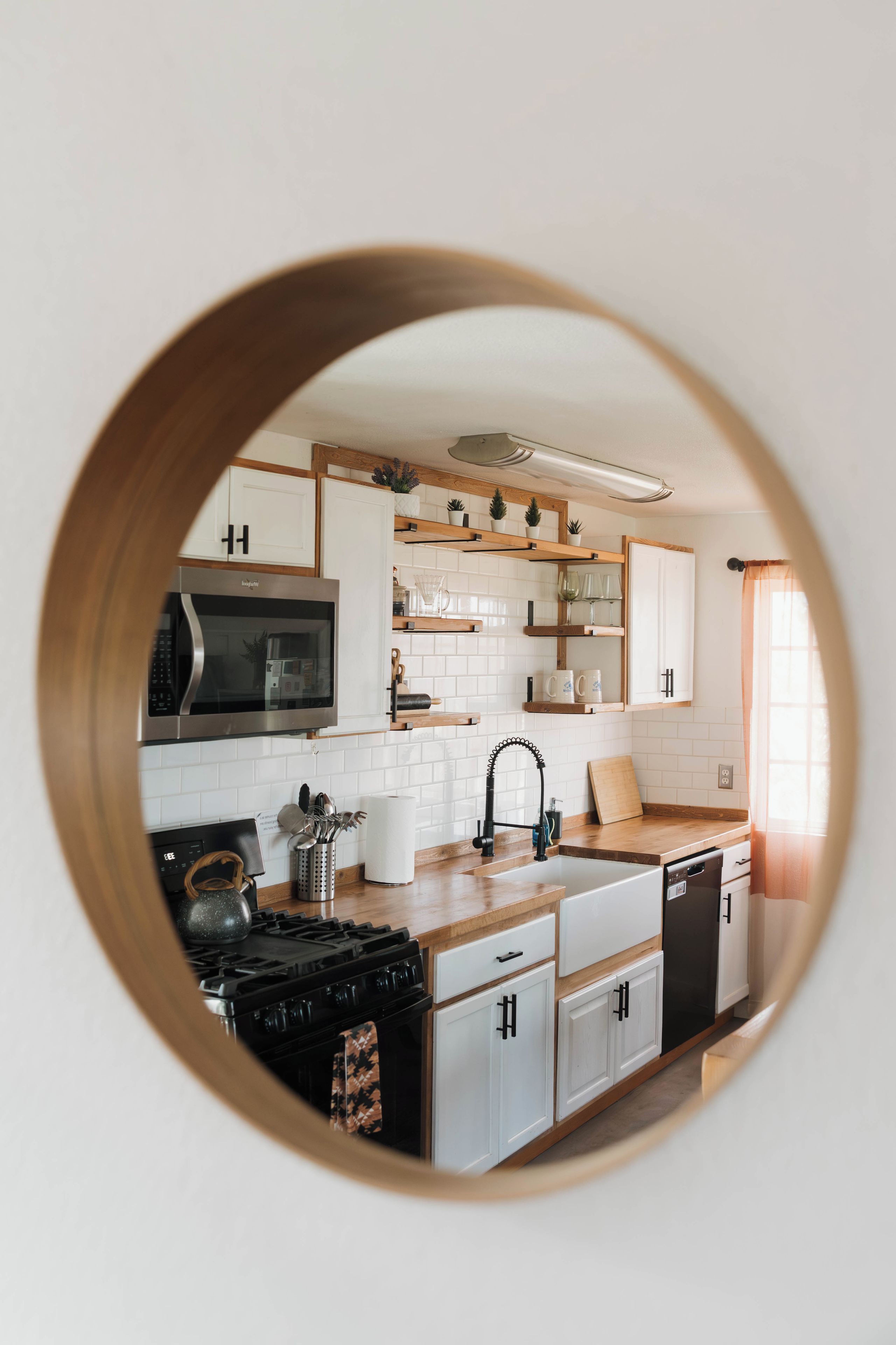 A kitchen with white cabinets, a black stove, and a wooden countertop.