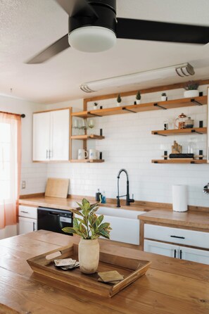Una cocina moderna con encimeras de madera, horno empotrado y ventilador de techo.