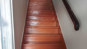 A staircase with a handrail on the right and a white wall on the left. - Studio nono (Pointe-à-Pitre)