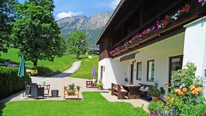Een chalet in traditionele stijl met een tuinpatio, buitenmeubels en uitzicht op de bergen.