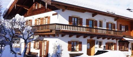 Una chaleta de varios pisos con balcones de madera y un paisaje nevado.