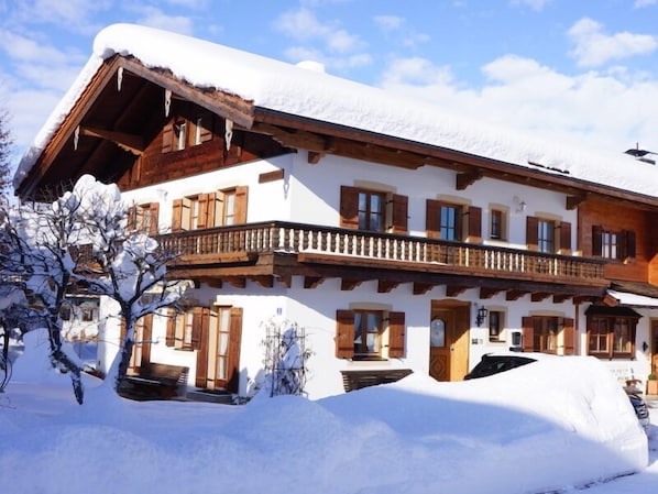 A multi-story chalet with wooden balconies and snow-covered surroundings.