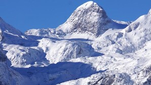 Une montagne enneigée, au relief accidenté, sous un ciel bleu dégagé.