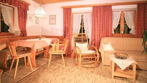 Una stanza accogliente con un tavolo da pranzo in legno, sedie, una poltrona a dondolo, un divano e un tavolino con un vassoio.