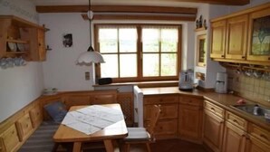 Eine Küche mit Holzausstattung, einem Esstisch mit Stühlen und einem Fenster mit Jalousien.
