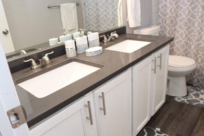 A bathroom with two sinks, a toilet, and a shower curtain with a giraffe pattern. - Cheerful, Newly  furnished 3 bdrm home with indoor fireplace. (Aurora)